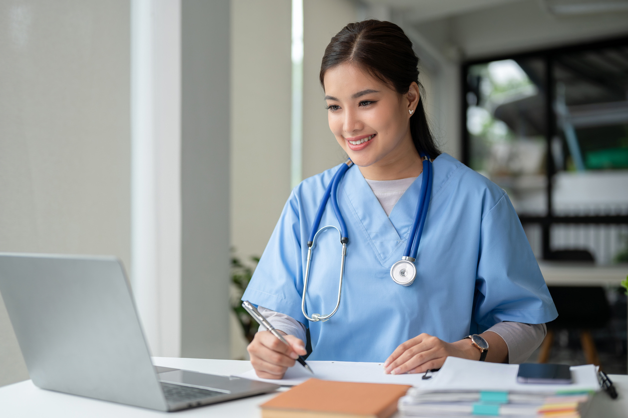 A school nurse works on a laptop in an office.