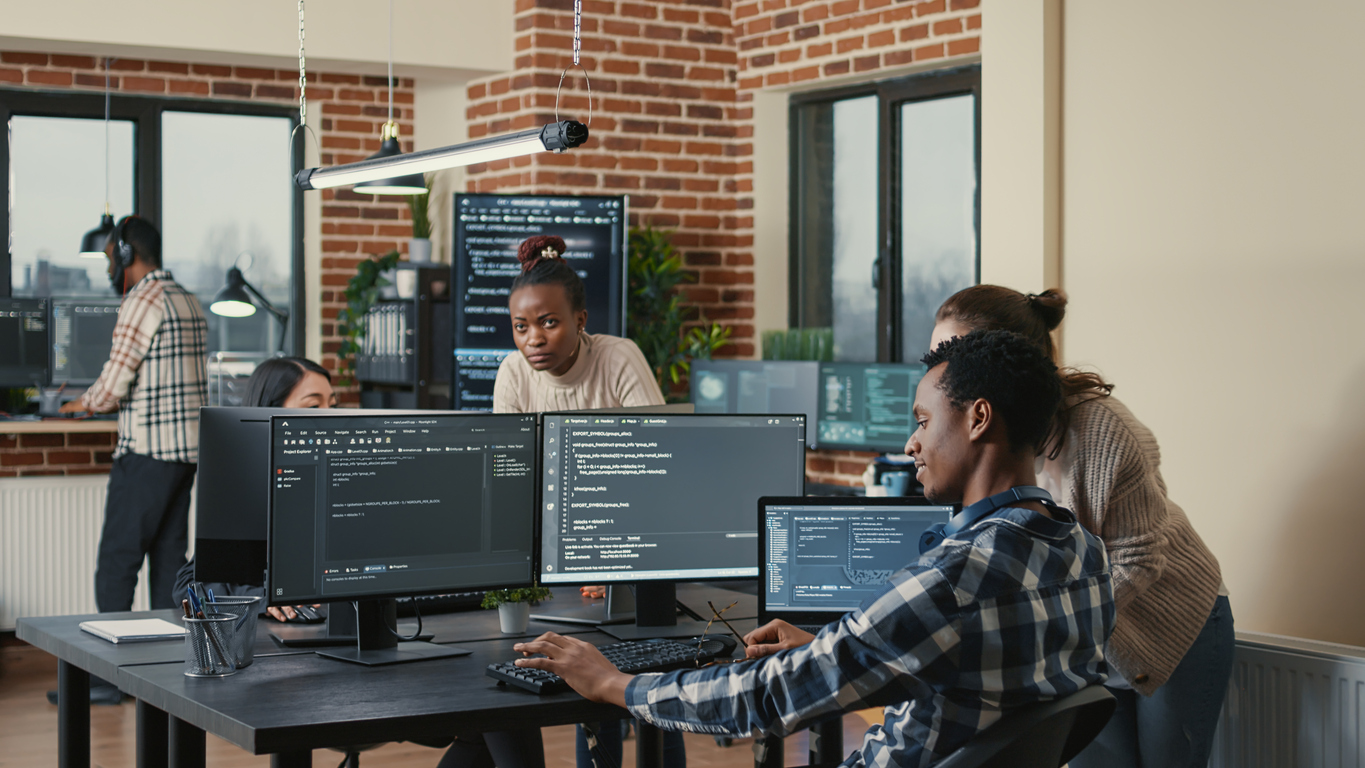 A cybersecurity team works on code in a busy office.