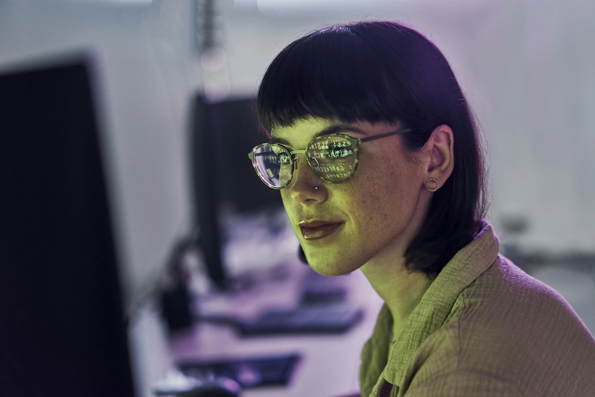 A cybersecurity professional with computer graphics reflected in their glasses.