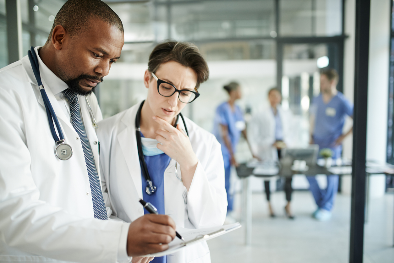 A Doctor and a Nurse Practitioner in White Coats Review a Patient’s Chart.
