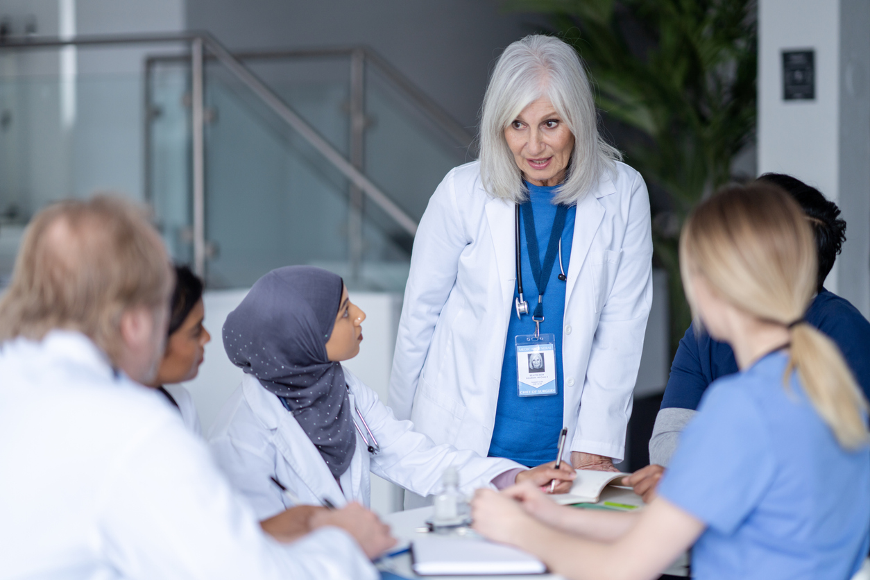 A chief nurse officer leads a meeting of care providers.